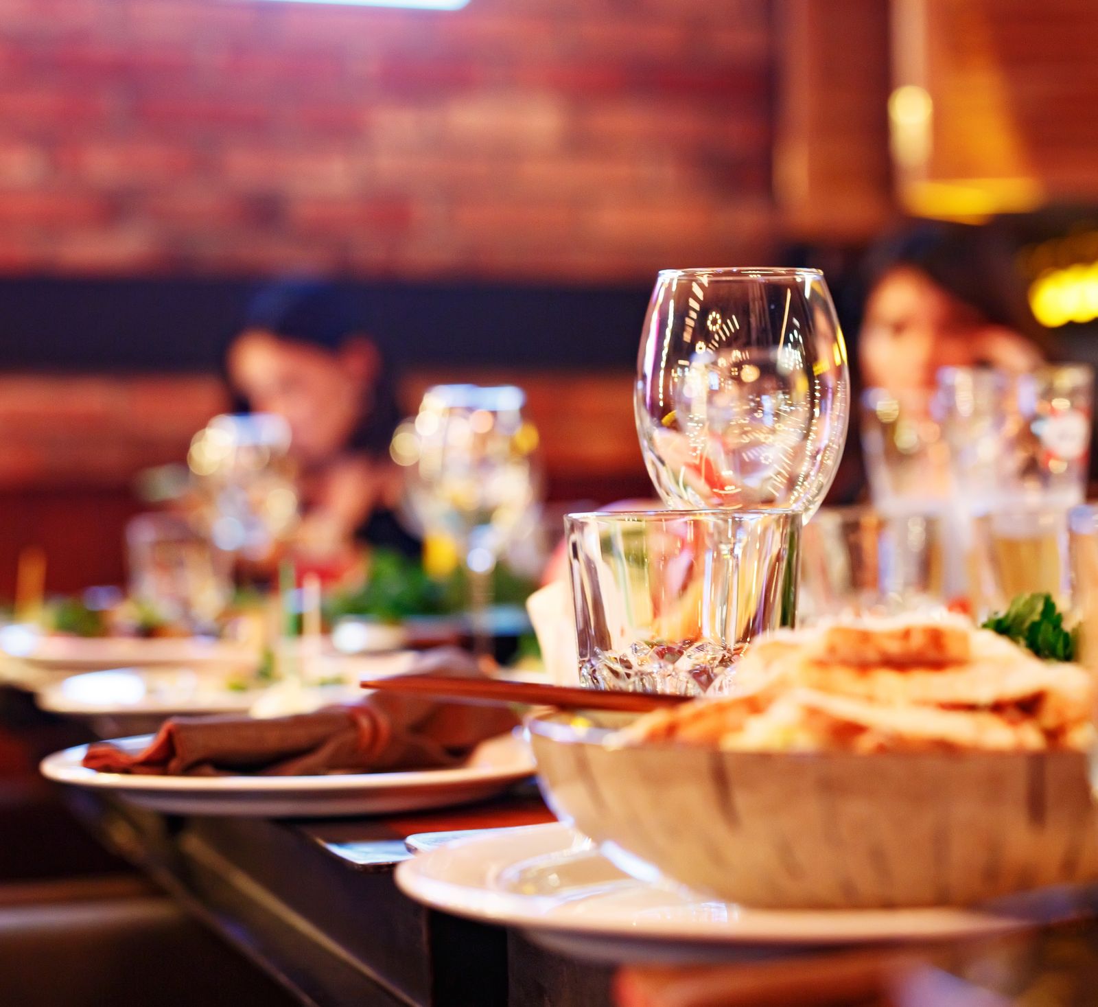 Restaurant table set with glasses and food as guests arrive